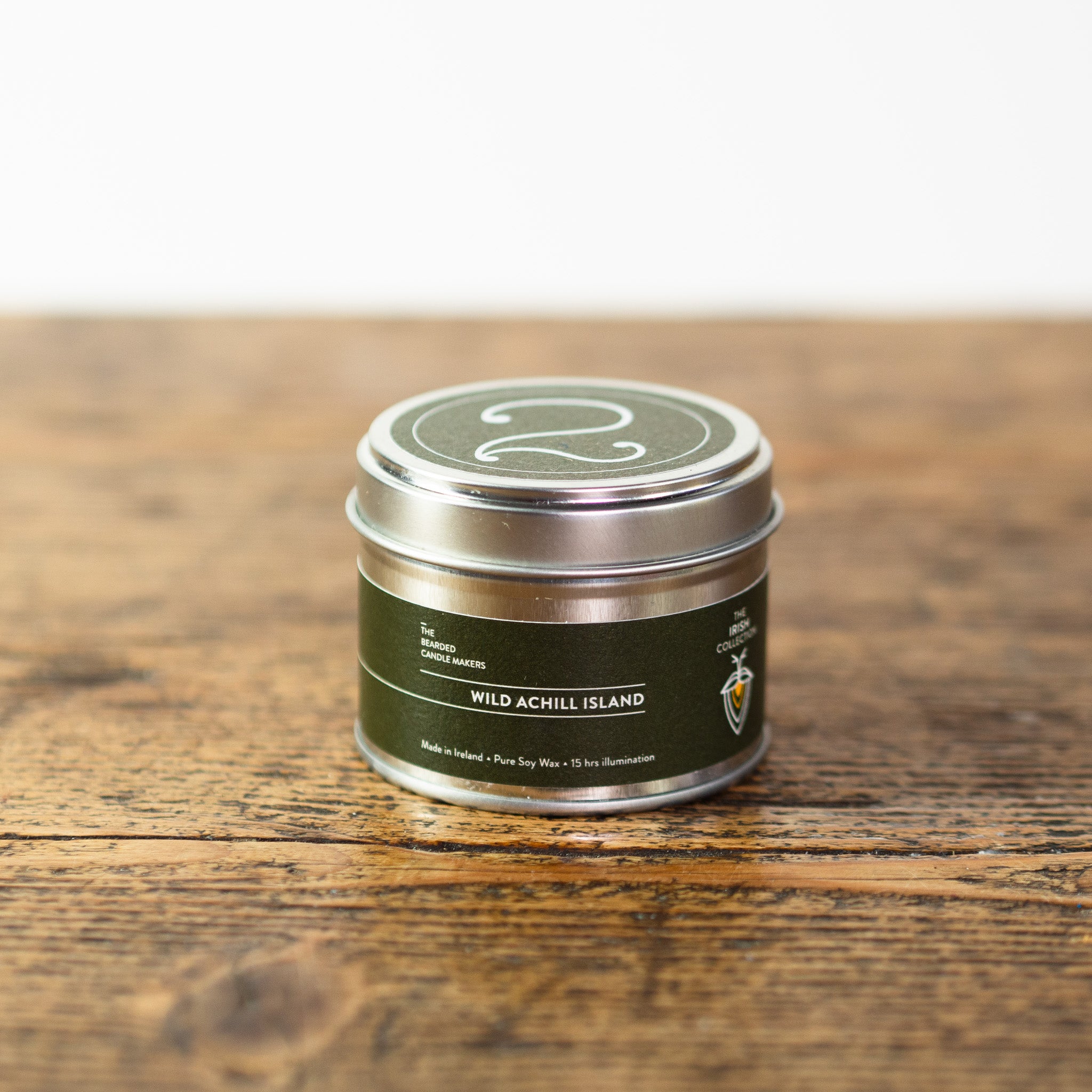 A photo of a candle tin, called Wild Achill Island on a wooden table