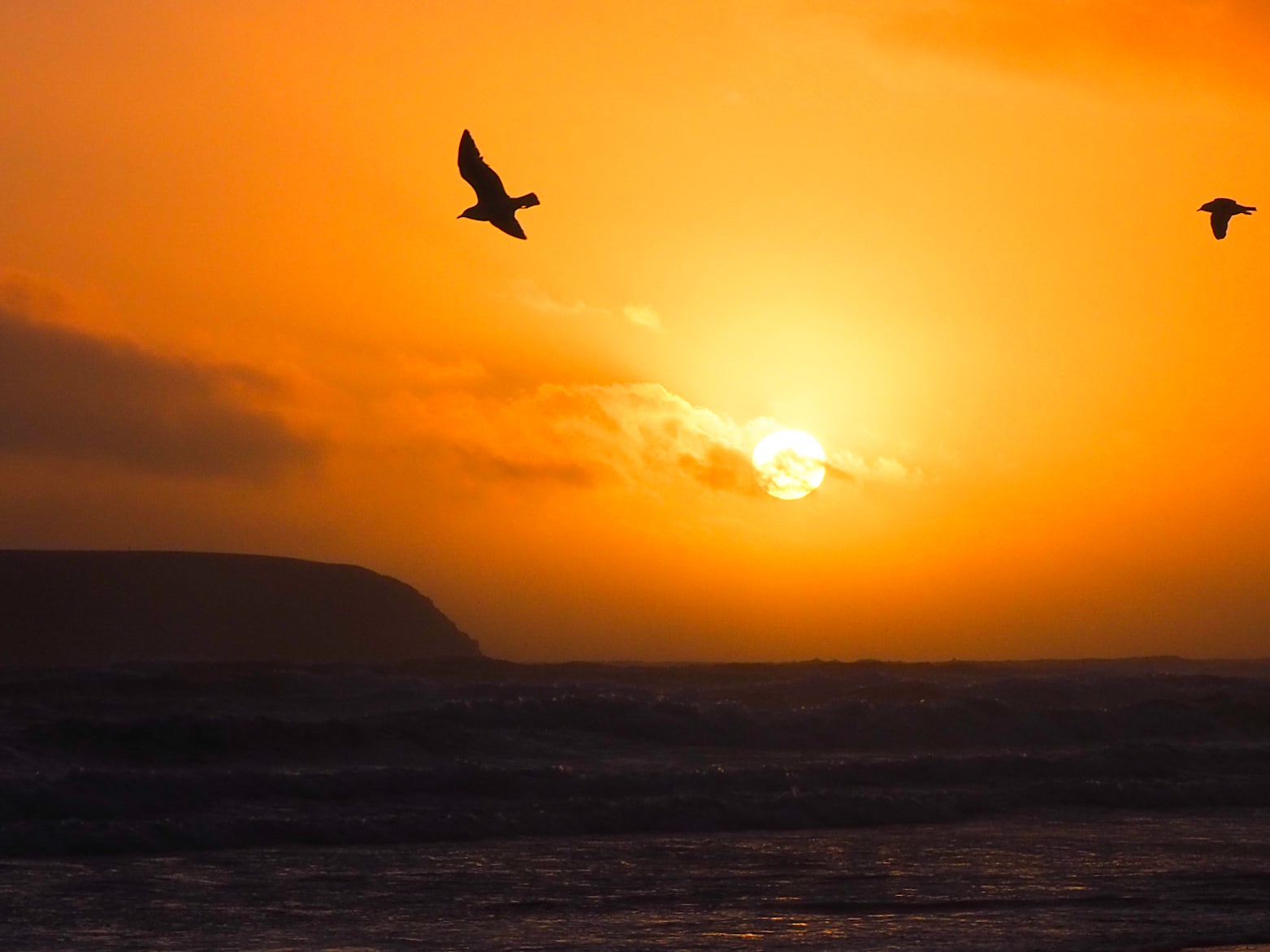 A photo at sunset from Achill Island looking out towards Clare Island. With birds in the sky.