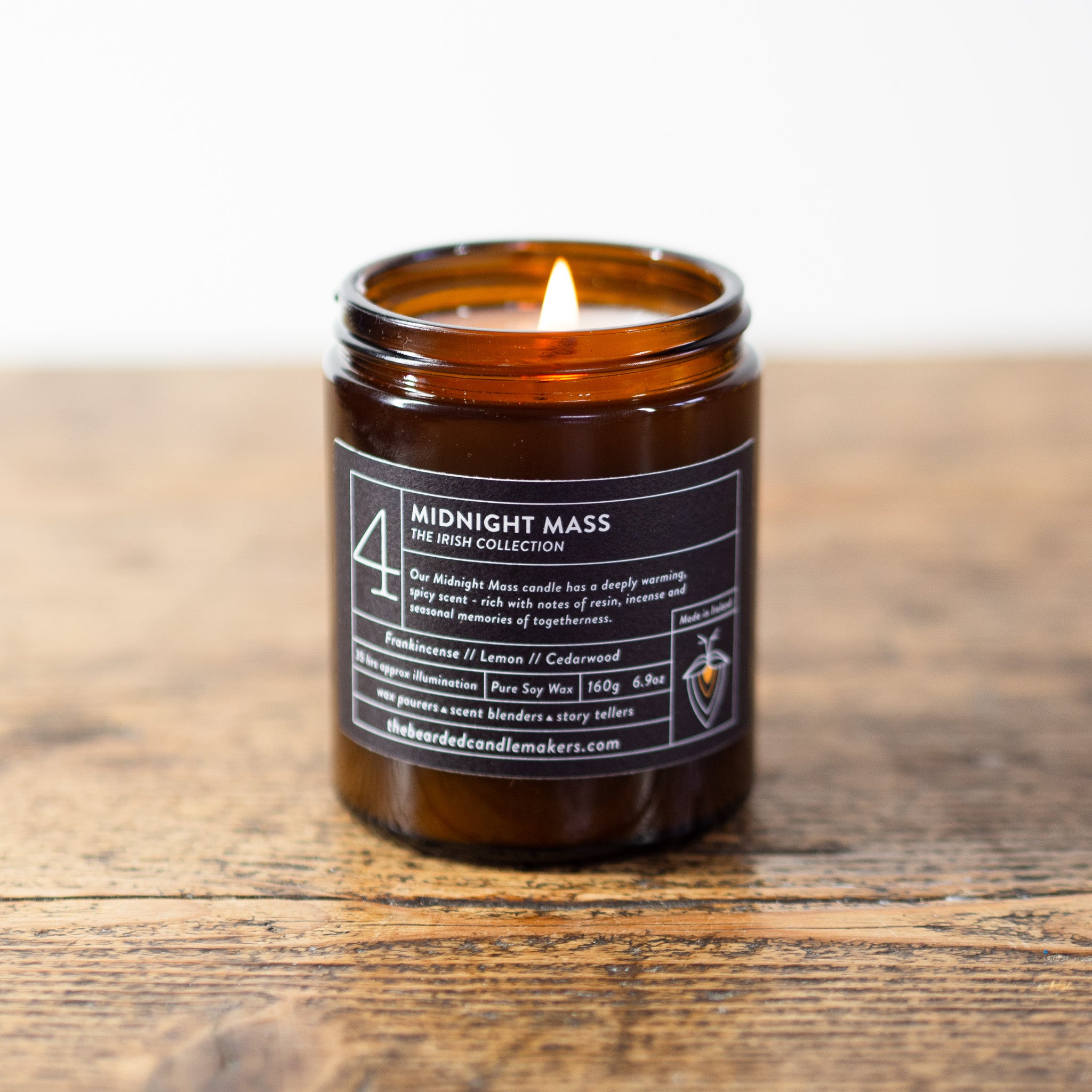 A photo of our Midnight Mass soy candle on a wooden table