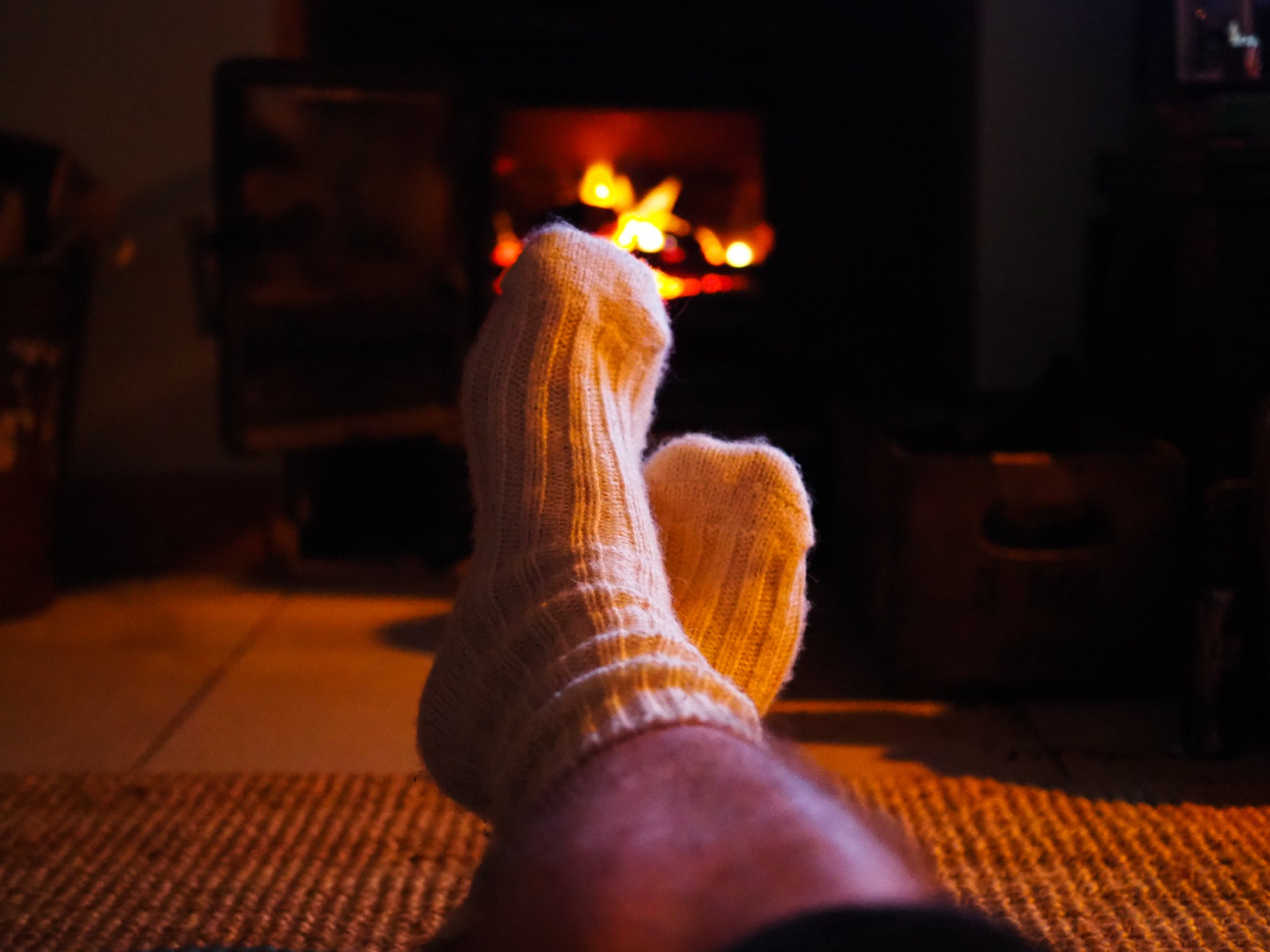 A photo of Michael wearing a pair of woollen socks in front of a turf fire